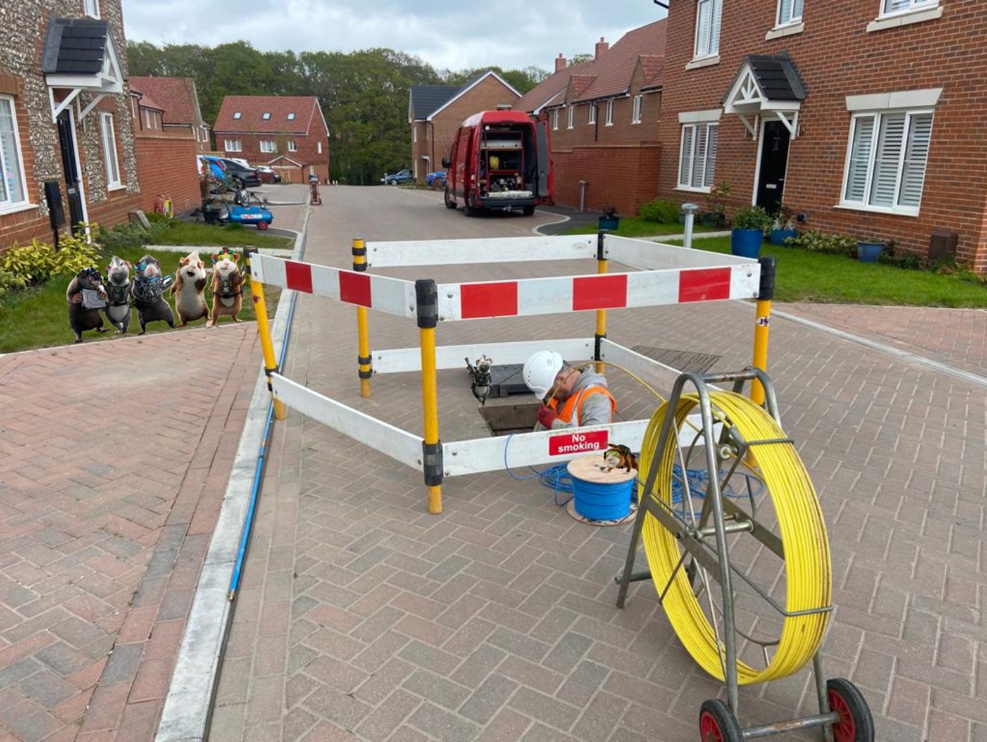 Barriered open manhole with drain rods on a block-paved street, G-Force van behind