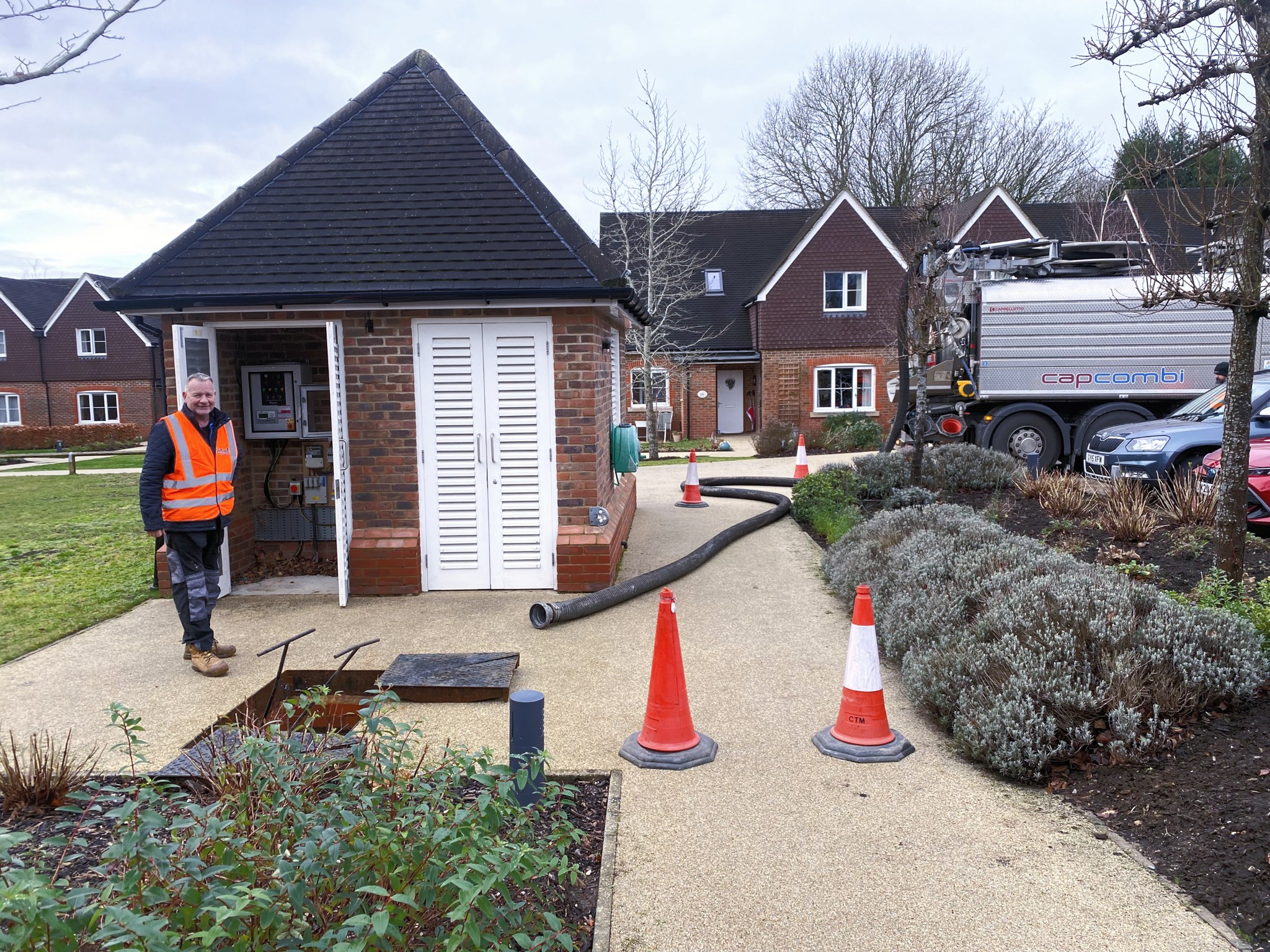 G-Force engineers running a hose to a pump house on a landscaped estate